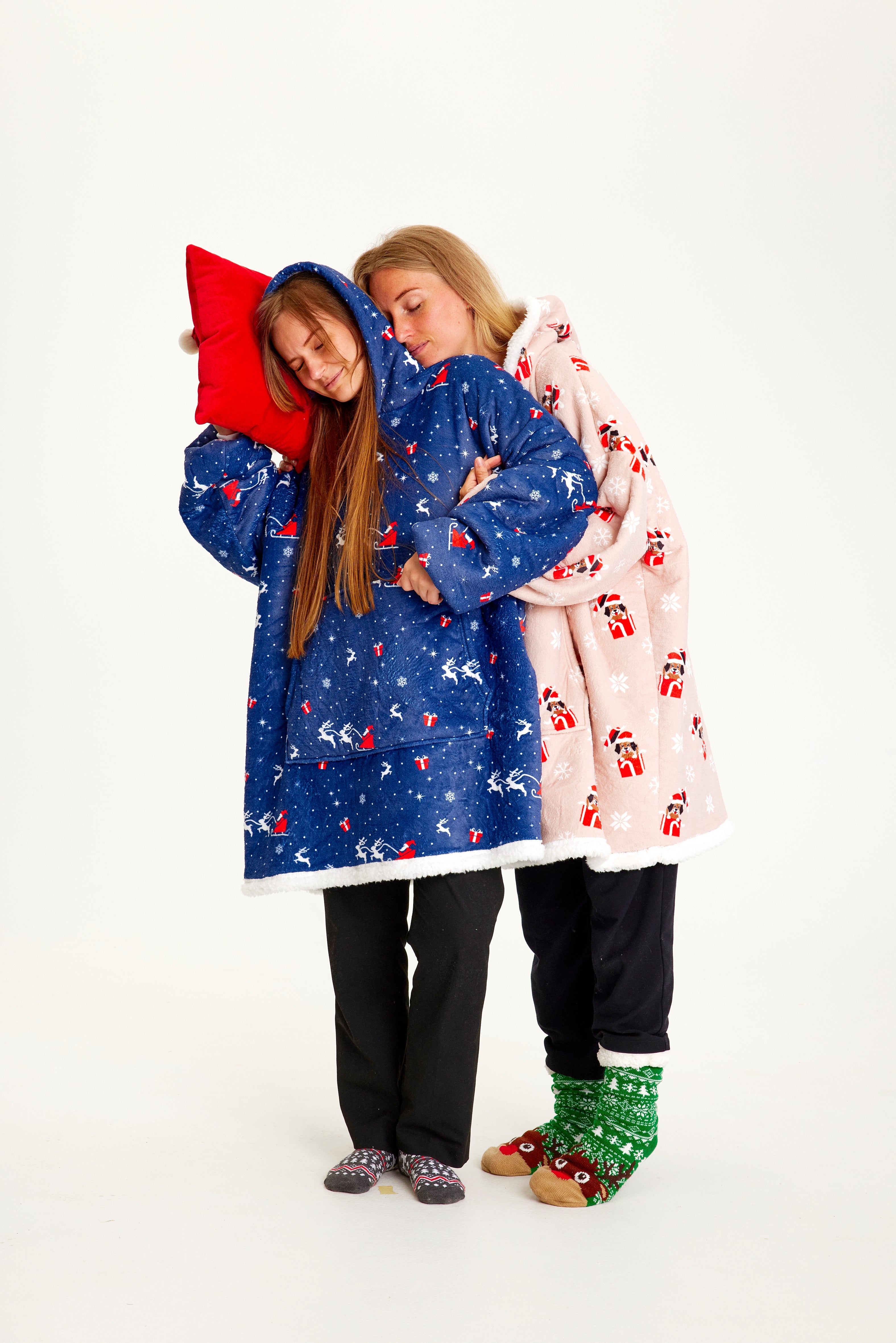 To kvinde holder om hinanden og poserer i hver deres julehoodie.